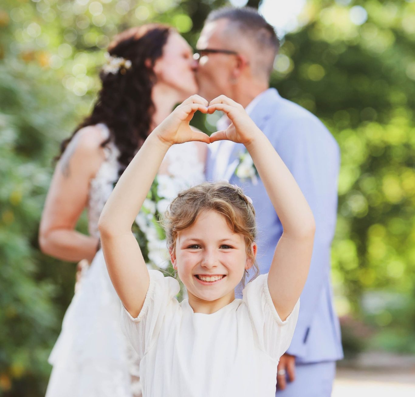 Kind lächelt und zeigt mit Händen ein Herz